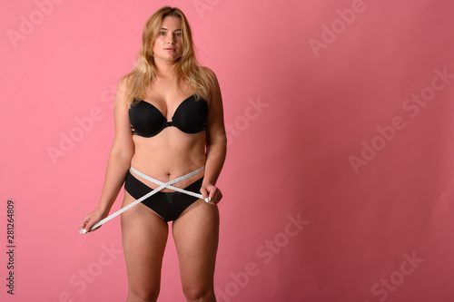 girl wearing black bikini measures the size of the waist