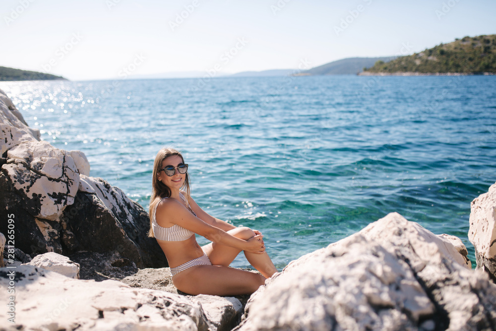 Sexy woman in sunbathing and enjoying summer sun on the rock. Woman on sea background. Relax on vocation Sexy woman in sunbathing and enjoying summer sun on the rock. Woman on sea background. Relax on vocation