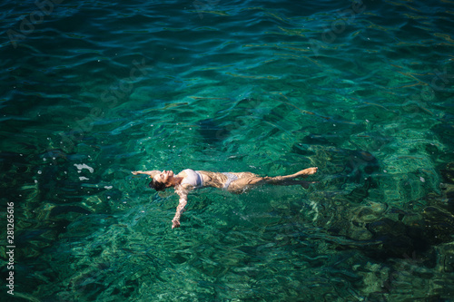 Sexy woman in bikini lying on the water. Attractive young woman enjoying summer sun. Beautiful lagoon. Woman swin in the sea. Top view