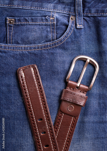 Men's belt and jeans closeup. Belt and jeans closeup. Top view on brown belt and blue jeans.