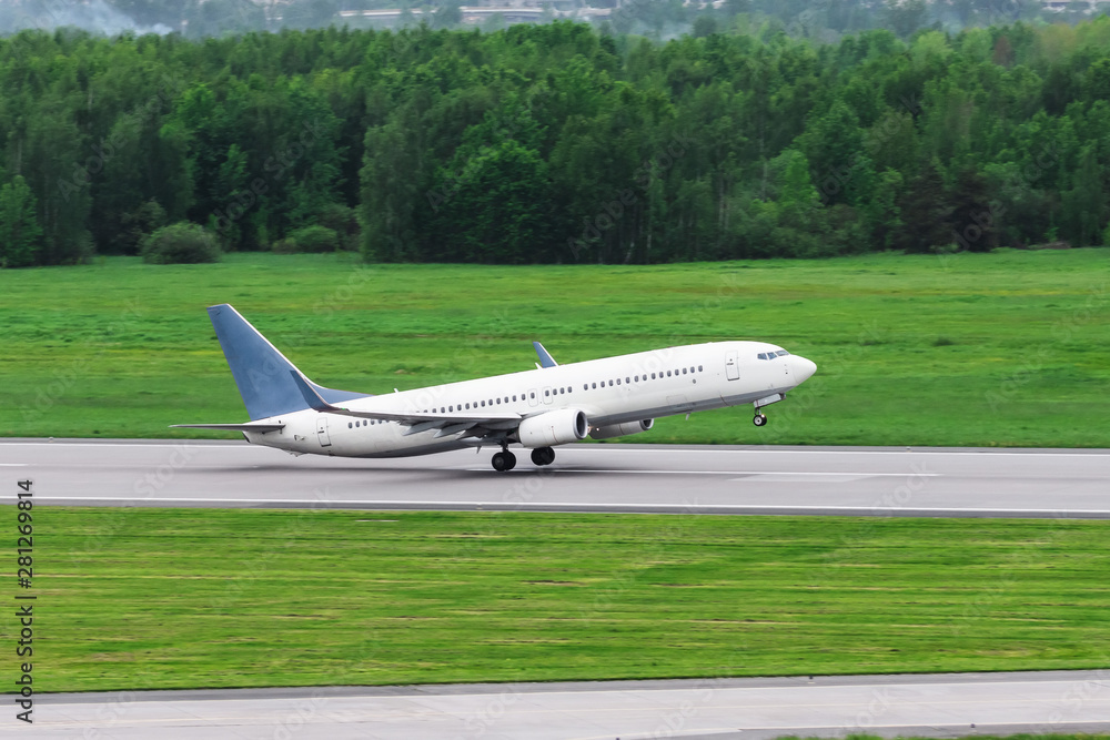 Passenger airplane takes off from the runway against the green forest. Passenger airplane takes off from the runway against the green forest.