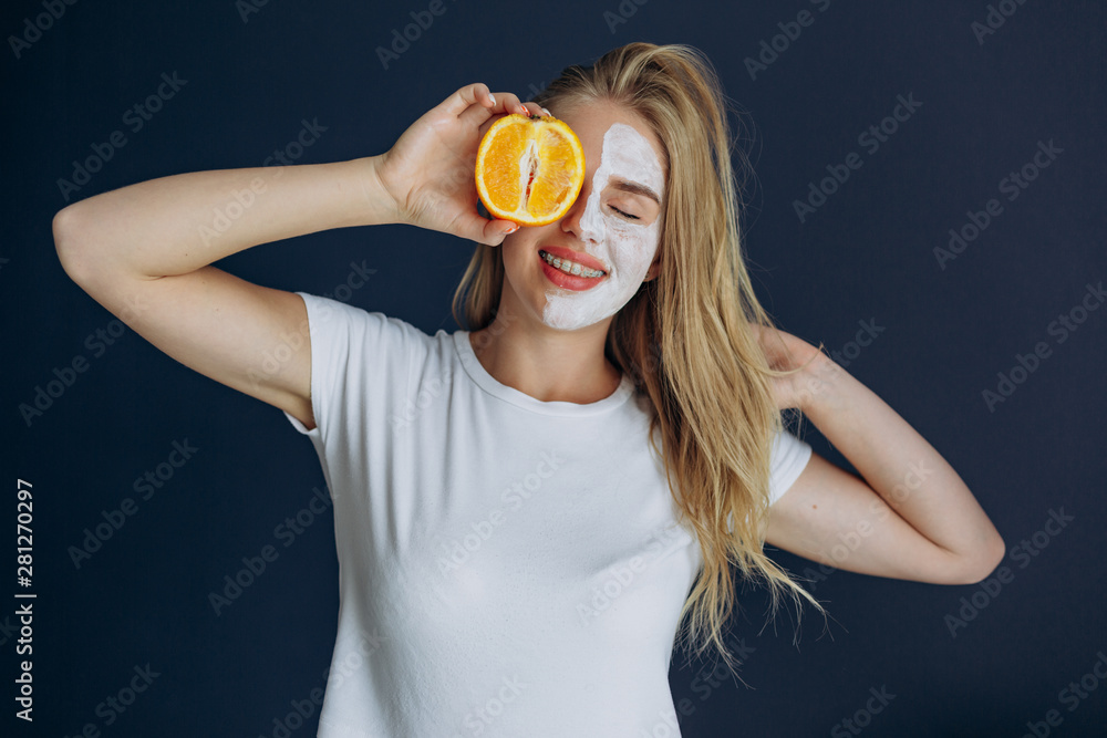 Woman with mask on half face , being playful covering her eye with orange Woman with mask on half face , being playful covering her eye with orange