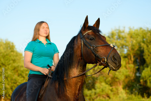 The young horsewoman is sitting astride the thoroughbred horse.