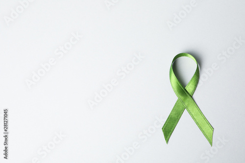Green awareness ribbon on grey background, space for text