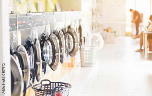Fotografija Row of industrial laundry machines in laundromat  in a public laundromat, with laundry in a basket ,