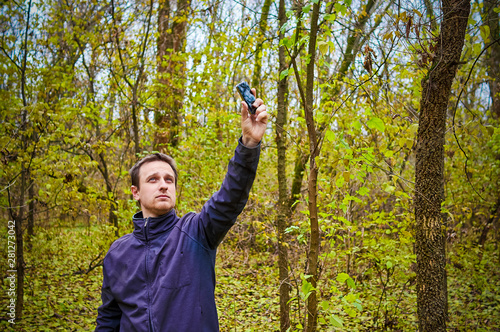 Man with his mobile smart phone searching for reception signal in the forest.