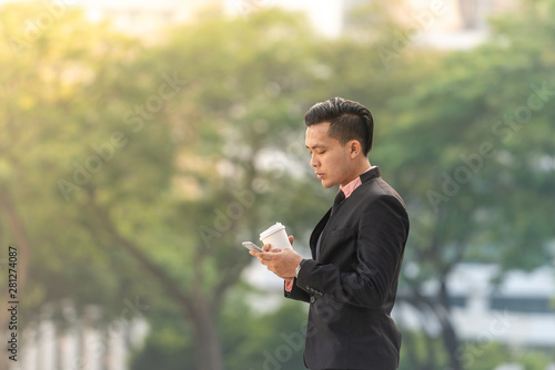 Young Malay Business Man on his Smartphone with a cup of coffee. Copy space for text.