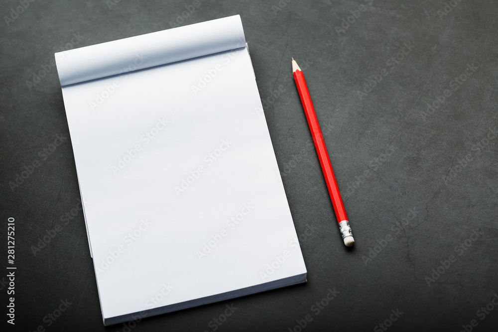 Notepad with a red pencil on a black stone plate background, for education, recording goals and deeds Notepad with a red pencil on a black stone plate background, for education, recording goals and deeds