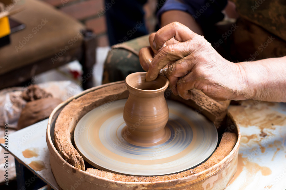 a potter makes a pot of clay on a potter's wheel, hands close up a potter makes a pot of clay on a potter's wheel, hands close up