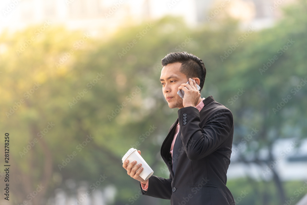 Young Malay Business Man on his Smartphone with a cup of coffee. Copy space for text. Young Malay Business Man on his Smartphone with a cup of coffee. Copy space for text.