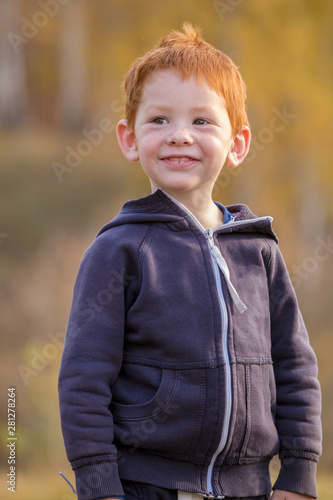 Adorable little boy standing on autumn landscape