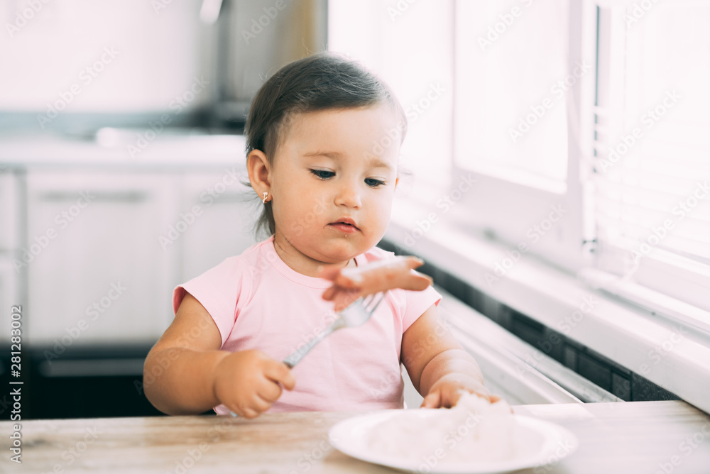 Little baby girl in the kitchen eating sausage and mashed potatoes Little baby girl in the kitchen eating sausage and mashed potatoes