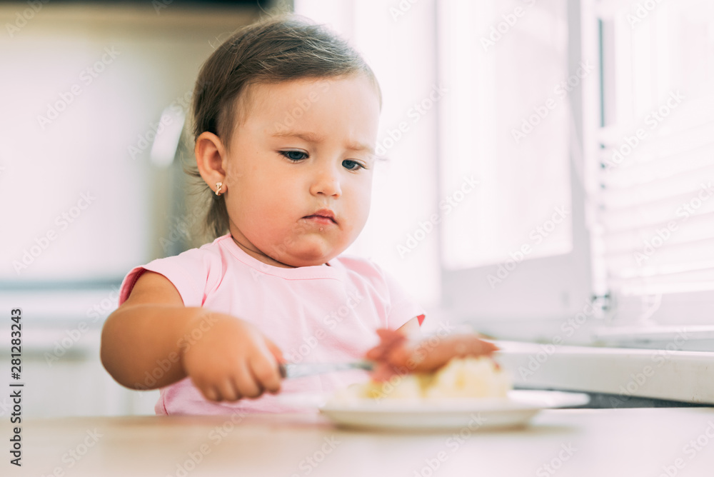 Little baby girl in the kitchen eating sausage and mashed potatoes Little baby girl in the kitchen eating sausage and mashed potatoes