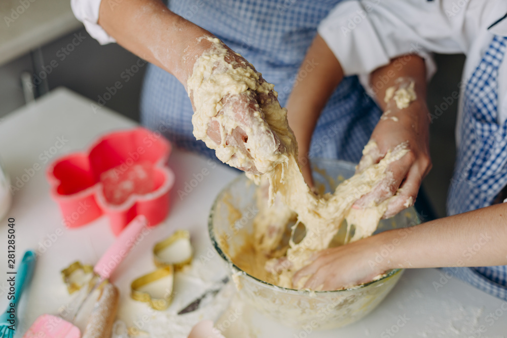 Closeup daughter and mother are stir the dough together and dirty they arms- Image