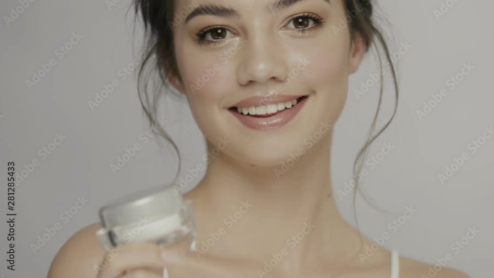 beautiful model showing white bottle of cream and smiling to camera beautiful model showing white bottle of cream and smiling to camera