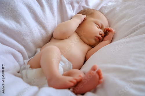 Newborn boy sleeping in a blanket on the bed