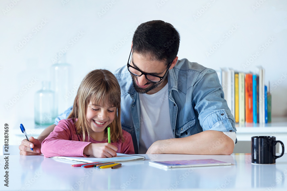 Handsome young father with his daughter drawing on notebook at home. Handsome young father with his daughter drawing on notebook at home.