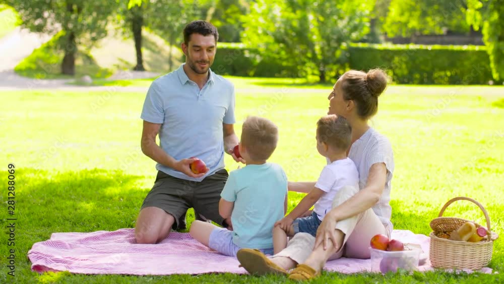 family, leisure and people concept - happy mother, father juggling apples and two little sons having picnic at summer park family, leisure and people concept - happy mother, father juggling apples and two little sons having picnic at summer park