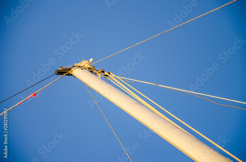 Sail boat mast, bracing, hemp ropes, blue sky. Minimalist maritime theme. History of water transport