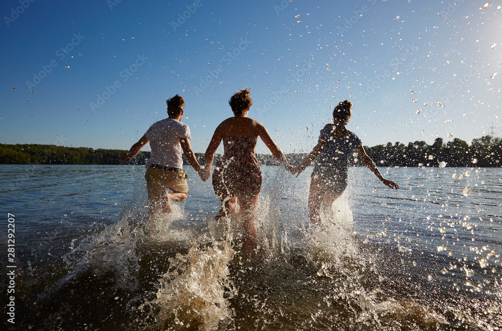 Back view of friends running in a lake Back view of friends running in a lake