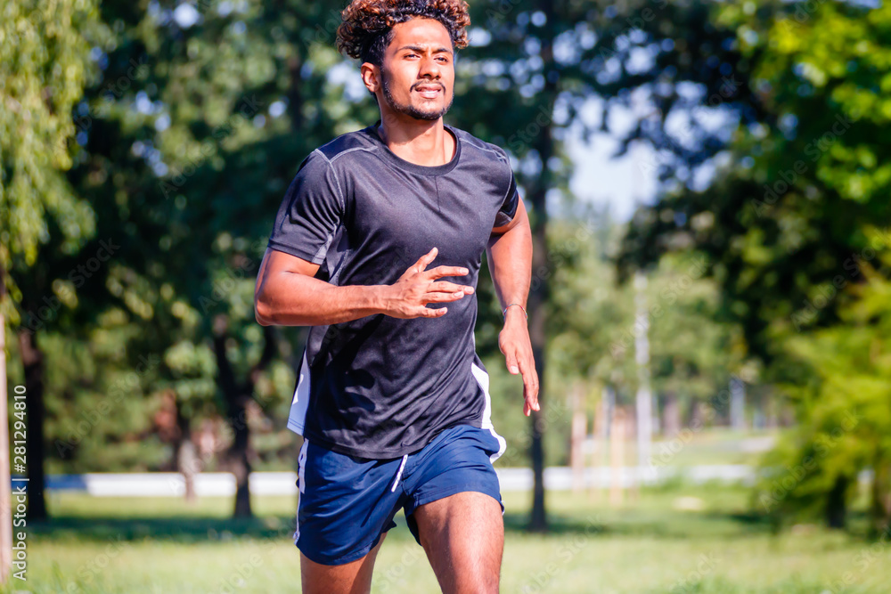 Active athletic young man running in the park with determination