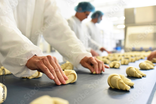 Workers at production line in a baking factory with croissants photo