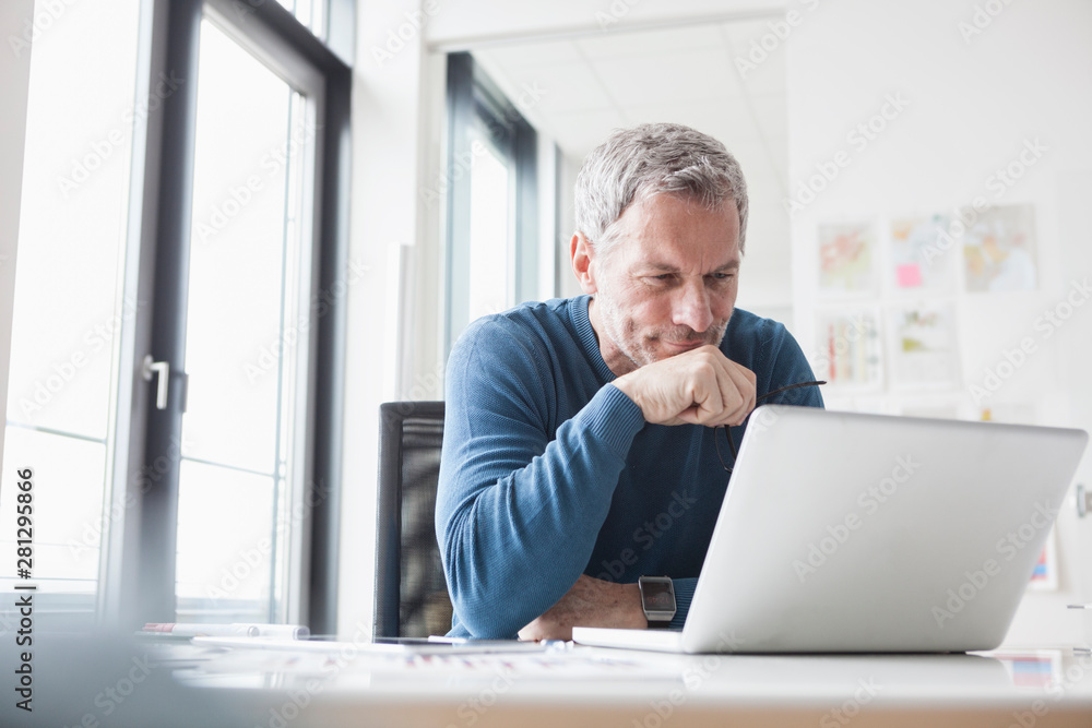 Mature man sitting in office using laptop Mature man sitting in office using laptop