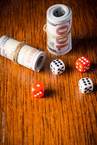 Gambling concept: rolled up money bills with dices on a wooden background