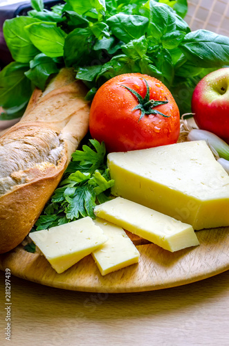 A vertical shot of a delicious quick snack of a ploughman’s lunch with French bread mature cheese a fresh tomato and an apple. 