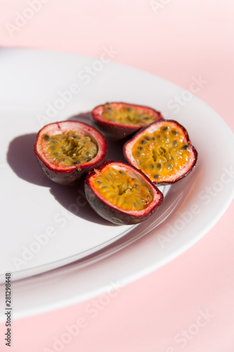 Fresh passion fruit on ceramic plate on a pastel pink background in top view. Ripe tropical passion fruit close up. Dessert of Vegetarian diet. intermittent fasting diet. Healthy snack.