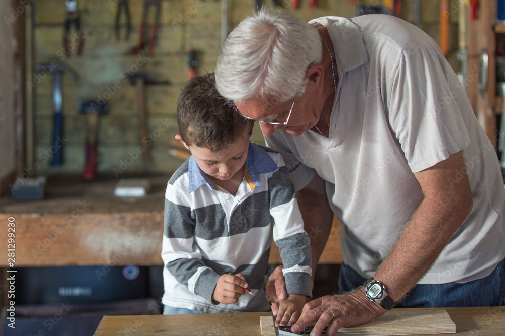 Grandfather and grandson working with wood in a garage Grandfather and grandson working with wood in a garage
