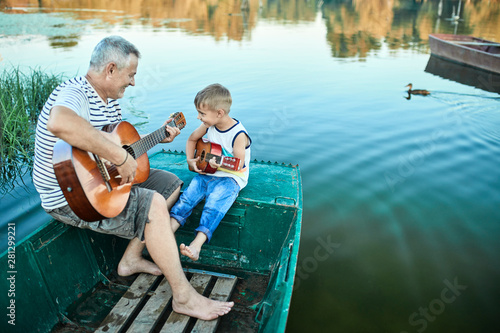 Grandfather teaching grandson playing guitar