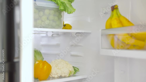 healthy eating, food and diet concept - female's hand opening fridge with vegetables at kitchen