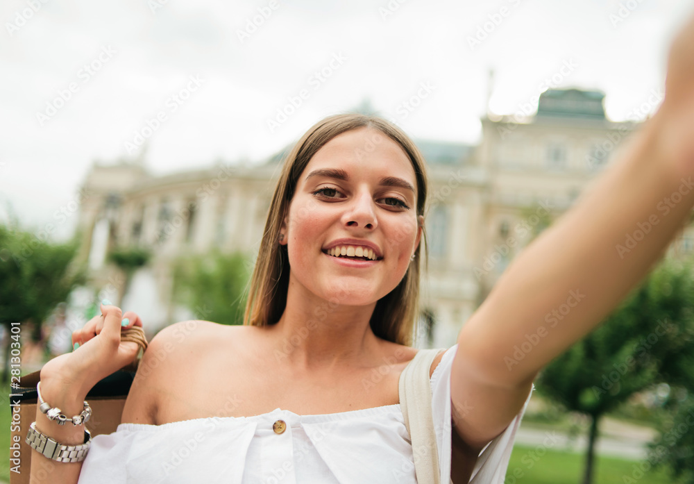 Cheerful attractive woman with shopping bags taking selfie portait outdoor