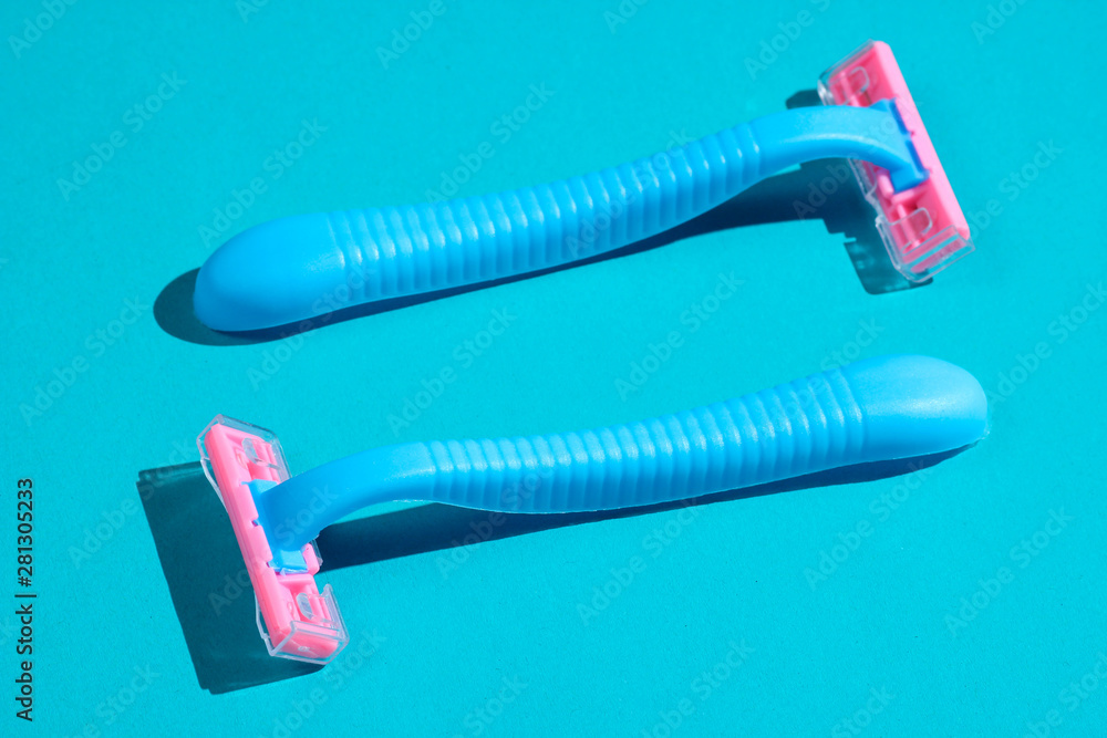 Two plastic razors on blue background. Minimalistic beauty and fashion concept Two plastic razors on blue background. Minimalistic beauty and fashion concept
