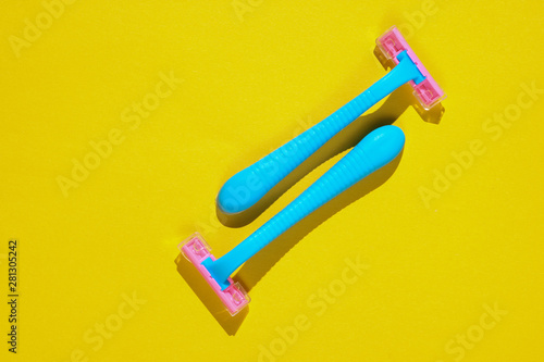 Two blue plastic razors on yellow background. Minimalistic beauty and fashion concept
