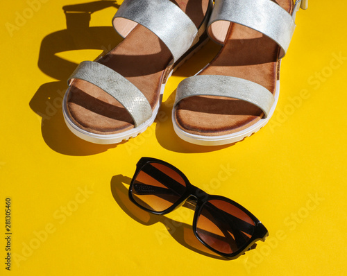 Fashionable women's sandals with sunglasses on a yellow background. Summer accessories