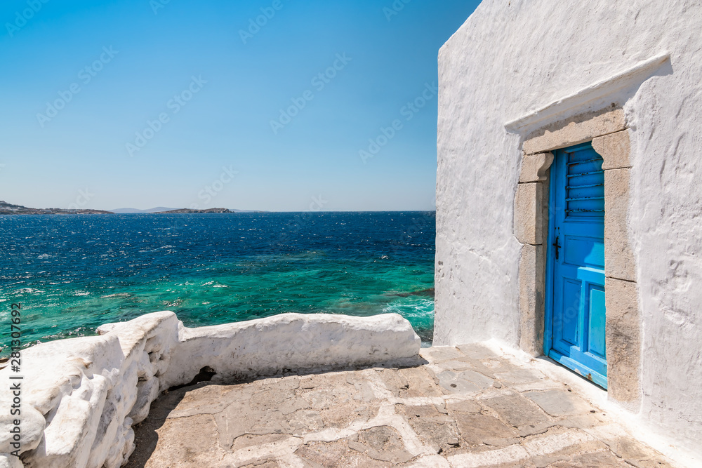 Mykonos, Greece. Traditional white building with blue door at the seaside.