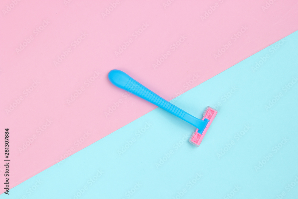 Minimalistic beauty concept. Plue plastic razor on blue pink pastel background. Top view Minimalistic beauty concept. Plue plastic razor on blue pink pastel background. Top view