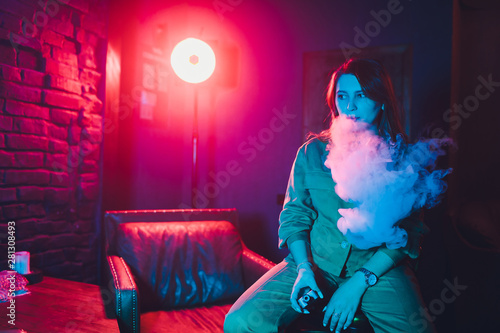 woman smokes a e-cigarette lying on the bed in the room. Smoker's concept Vaping. photo