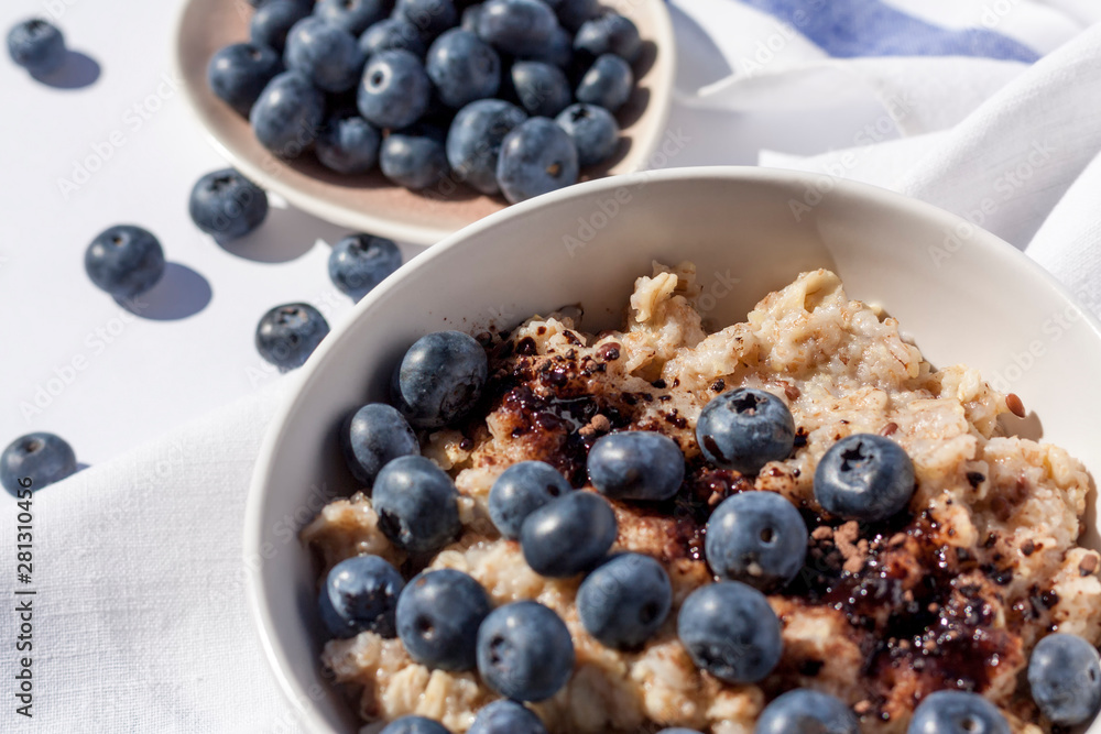 Oatmeal with blueberies and cocoa powder in a round bowl, Close. Oatmeal with blueberies and cocoa powder in a round bowl, Close.