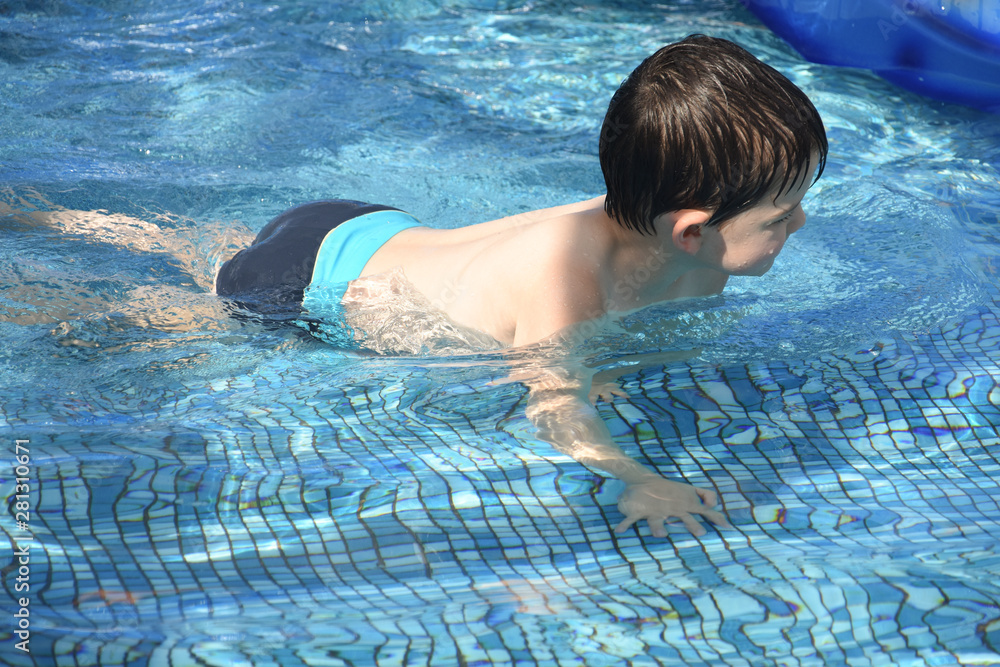 Little boy play swimming and playing in the pool. Cheerful child play in the swimming pool