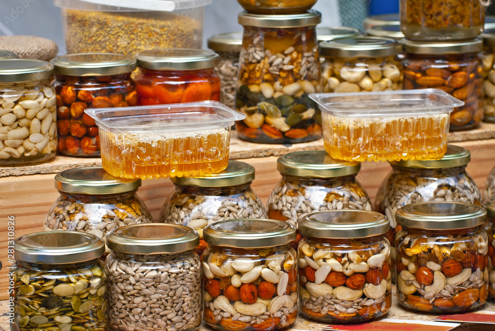 Lots of assorted honey on the table. Jars of sweets are sold at the fair. Honey with different kinds of nuts then dried fruits. Lots of assorted honey on the table. Jars of sweets are sold at the fair. Honey with different kinds of nuts then dried fruits.