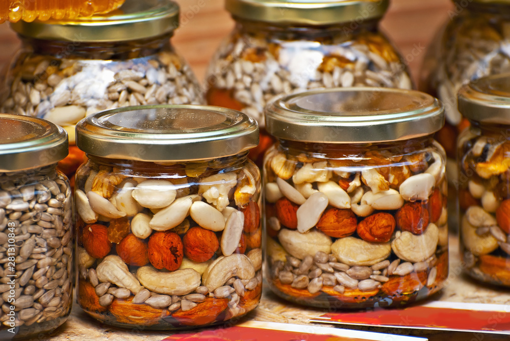 Lots of assorted honey on the table. Jars of sweets are sold at the fair. Honey with different kinds of nuts then dried fruits. Lots of assorted honey on the table. Jars of sweets are sold at the fair. Honey with different kinds of nuts then dried fruits.