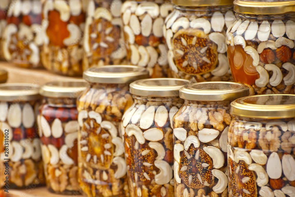 Lots of assorted honey on the table. Jars of sweets are sold at the fair. Honey with different kinds of nuts then dried fruits. Lots of assorted honey on the table. Jars of sweets are sold at the fair. Honey with different kinds of nuts then dried fruits.