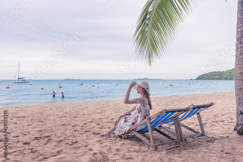 Fototapeta Naklejka Na Ścianę i Meble -  Summer beach vacation concept, Happy young Asian woman with hat relaxing on beach chair and raised hands up.