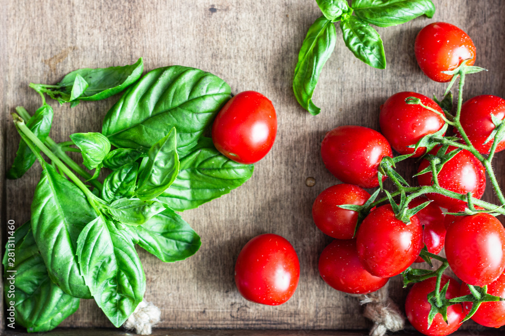 Fresh ripe cherry tomatoes and basil on a wooden background. Fresh ripe cherry tomatoes and basil on a wooden background.