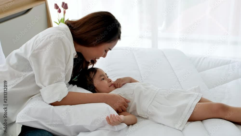 Asian family happy spending time together in the house. Mother kissing daughter aged three and enjoying playing on the bed. Happiness in the home. Asian family happy spending time together in the house. Mother kissing daughter aged three and enjoying playing on the bed. Happiness in the home.
