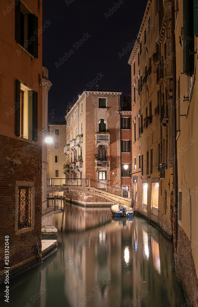 Stunning landscape of Venice at night. Long exposure photo of calm landscape of the city. Small boat in a calm canal at nighttime.