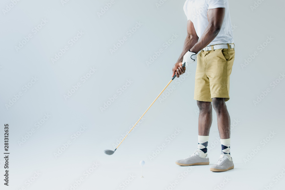 cropped view of african american sportsman in shorts playing golf on grey background cropped view of african american sportsman in shorts playing golf on grey background